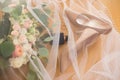 Beige brideÃ¢â¬â¢s shoes and other accessories are covered the veil. Wedding accessories: shoes, rings, perfume, bouquet. Royalty Free Stock Photo